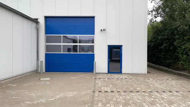 Lagerhallenanbau in Steinhagen – schlüsselfertige Erweiterung für Kleen Dichtungstechnik GmbH Lagerhallenanbau der Kleen Dichtungstechnik GmbH in Steinhagen mit blauer Toranlage und Hoffläche
